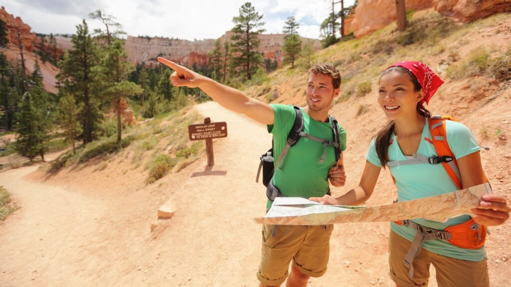 Couple holding paper map pointing up ahead on trail