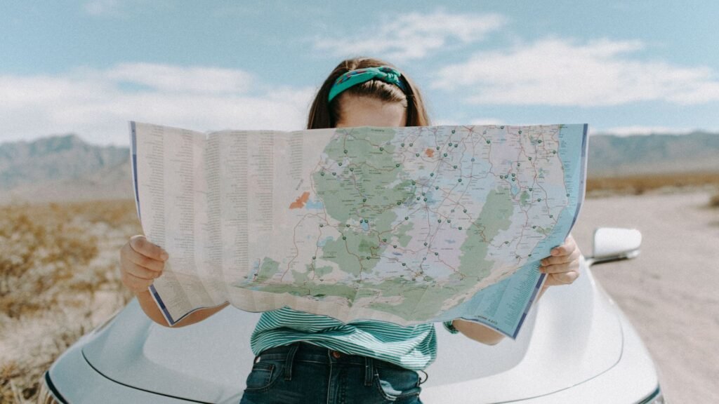 Female looking at open paper map outside a car